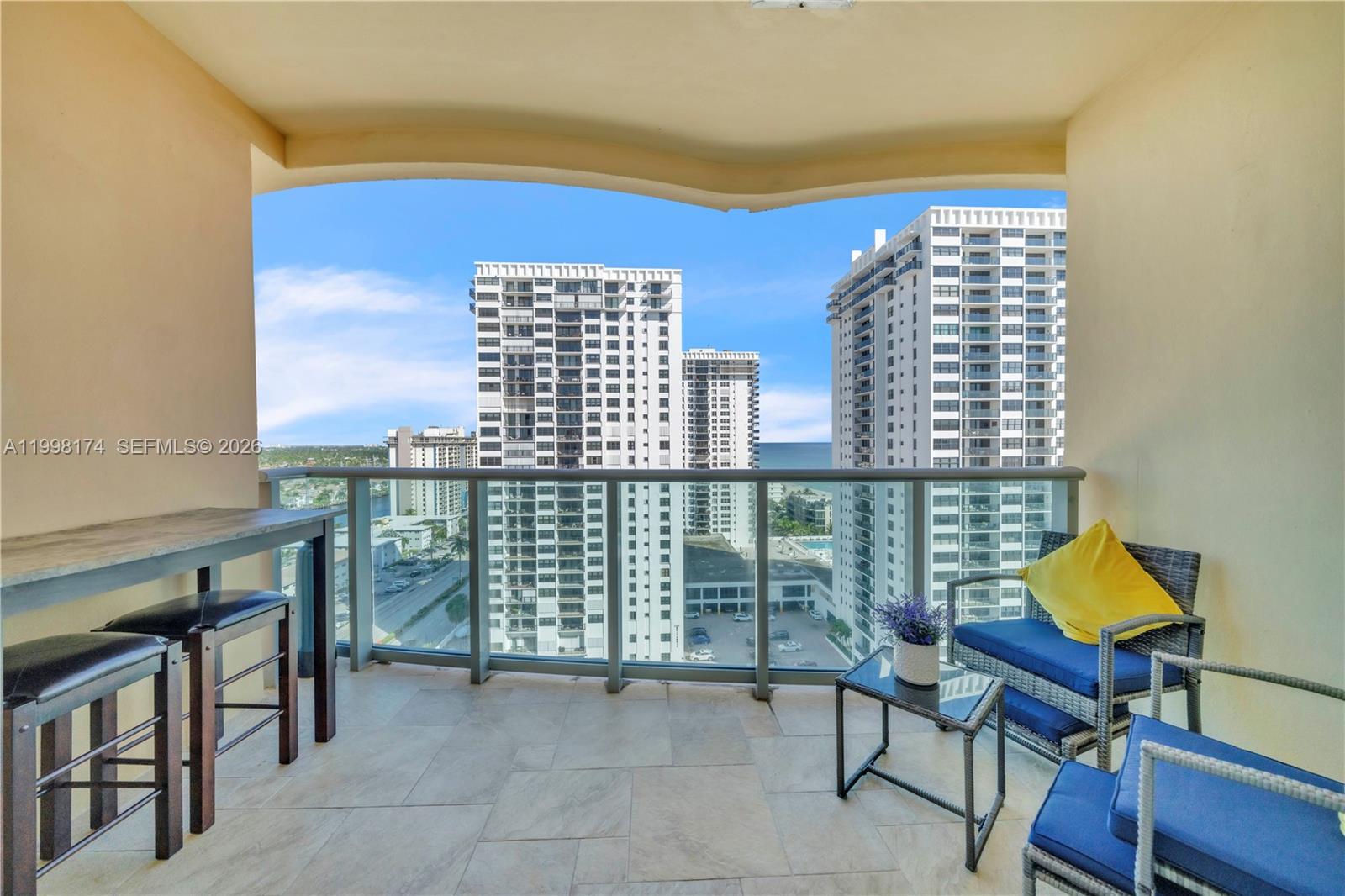 A balcony with outdoor furniture overlooks a city street and tall residential buildings — 2501 S Ocean Dr, Hollywood FL 33019, HOLLYWOOD, FL
