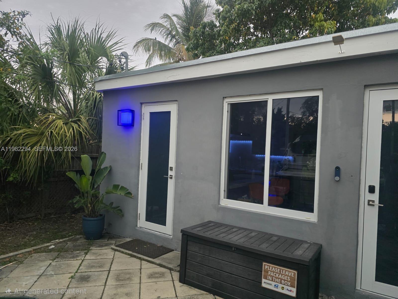 A gray exterior wall features a door, a window, a storage box, and blue lighting — 5812 NW 20th Ct, Margate FL 33063, MARGATE, FL