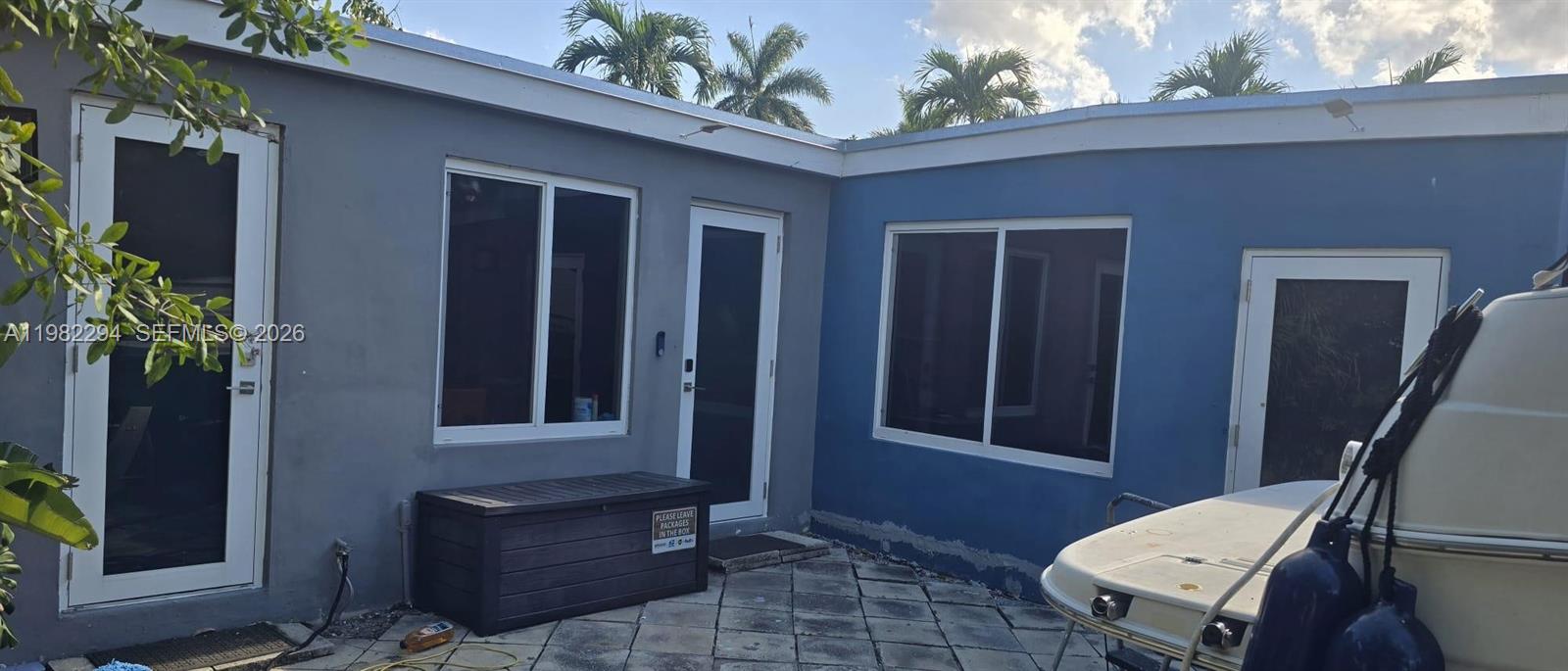 An exterior view shows a grey and blue house with multiple doors, windows, and a patio — 5812 NW 20th Ct, Margate FL 33063, MARGATE, FL