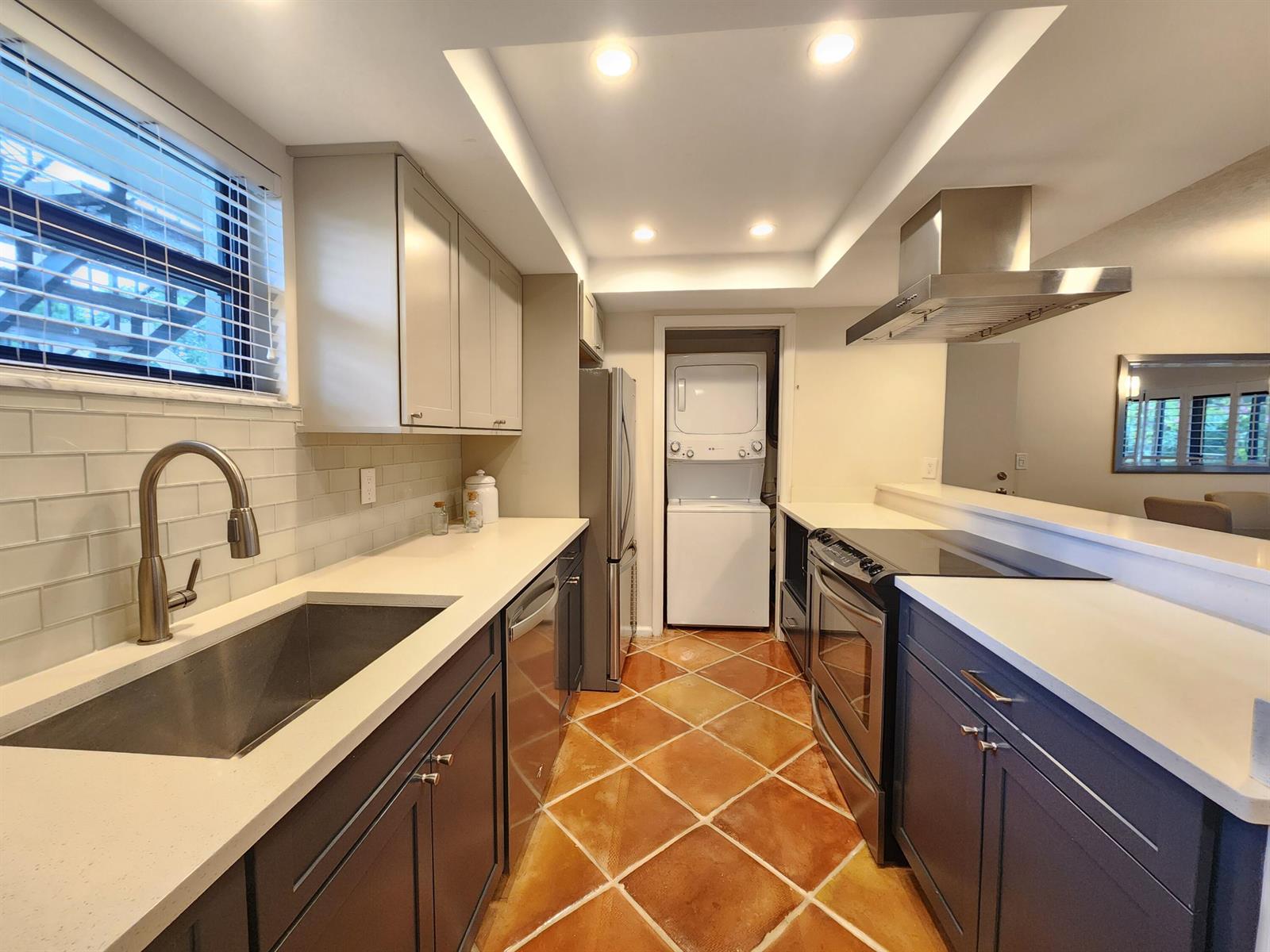 A kitchen features dark lower cabinets, light upper cabinets, white countertops, and terracotta floor tiles — 11863 Wimbledon Circle # 416, Wellington FL 33414, WELLINGTON, FL