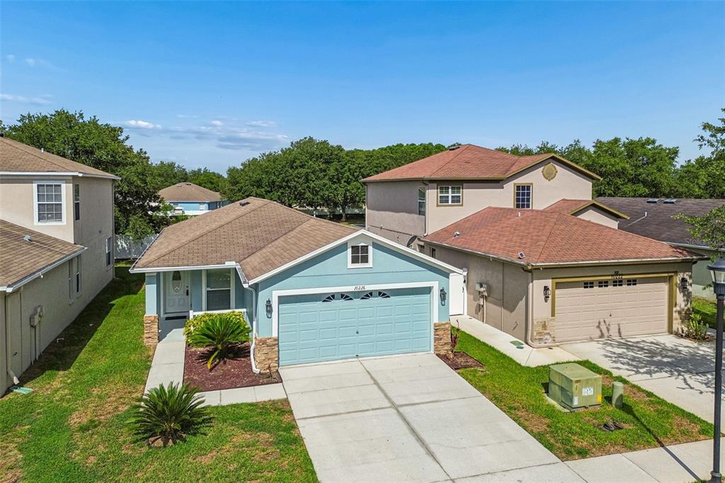 An aerial view shows the backyards and rear exteriors of three suburban houses with white fences — 10226 PERTHSHIRE CIRCLE, LAND O LAKES, FL