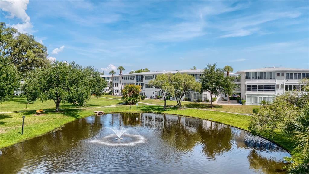 An exterior view of a multi-story apartment building overlooking a pond with a water fountain — 11251 80TH AVENUE UNIT 202, SEMINOLE, FL
