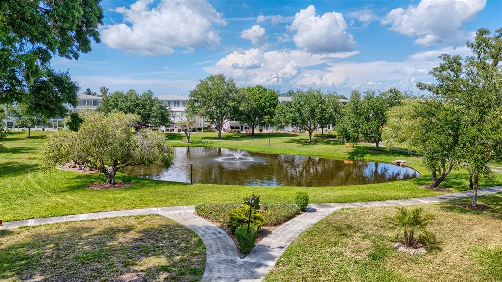 A pond with a fountain sits in the center of a grassy residential courtyard — 11251 80TH AVENUE UNIT 202, SEMINOLE, FL