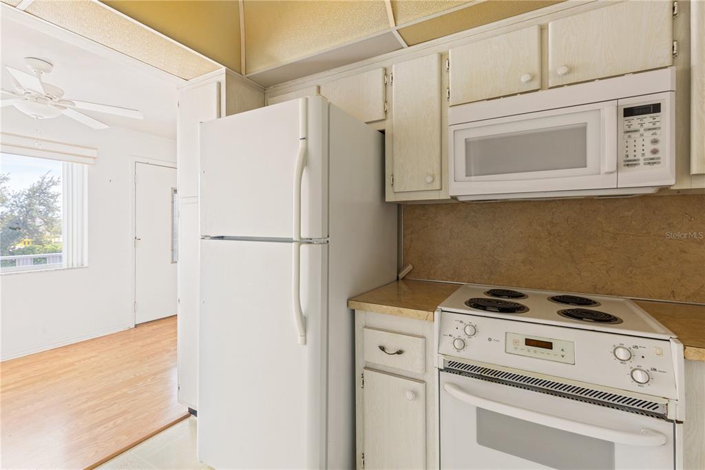 A kitchen features white appliances, light-colored cabinets, and a tan laminate countertop — 11251 80TH AVENUE UNIT 202, SEMINOLE, FL