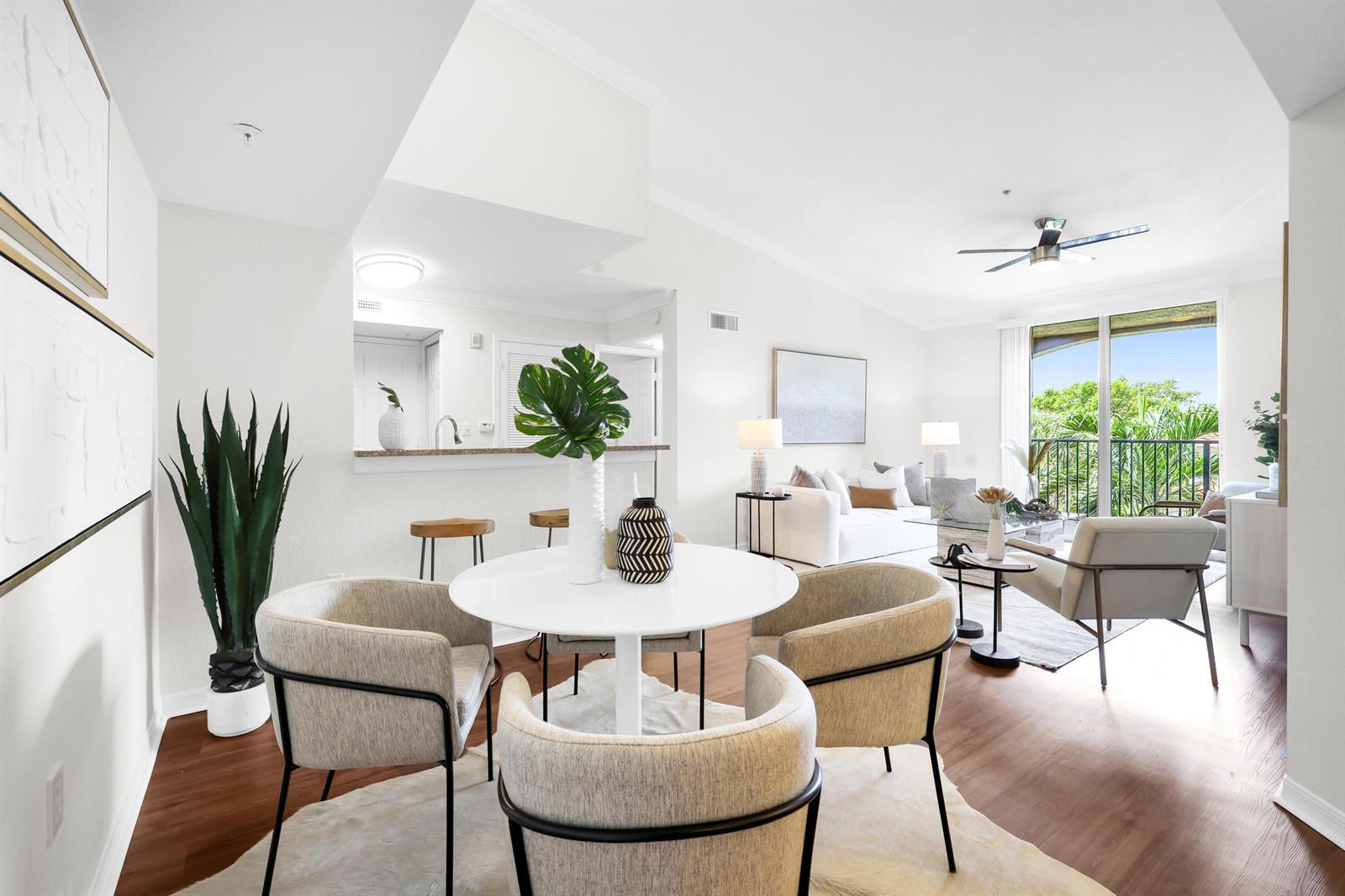A bright living and dining area features a white round table, chairs, and balcony access — 15035 Michelangelo Boulevard # 303, Delray Beach FL 33446, DELRAY BEACH, FL