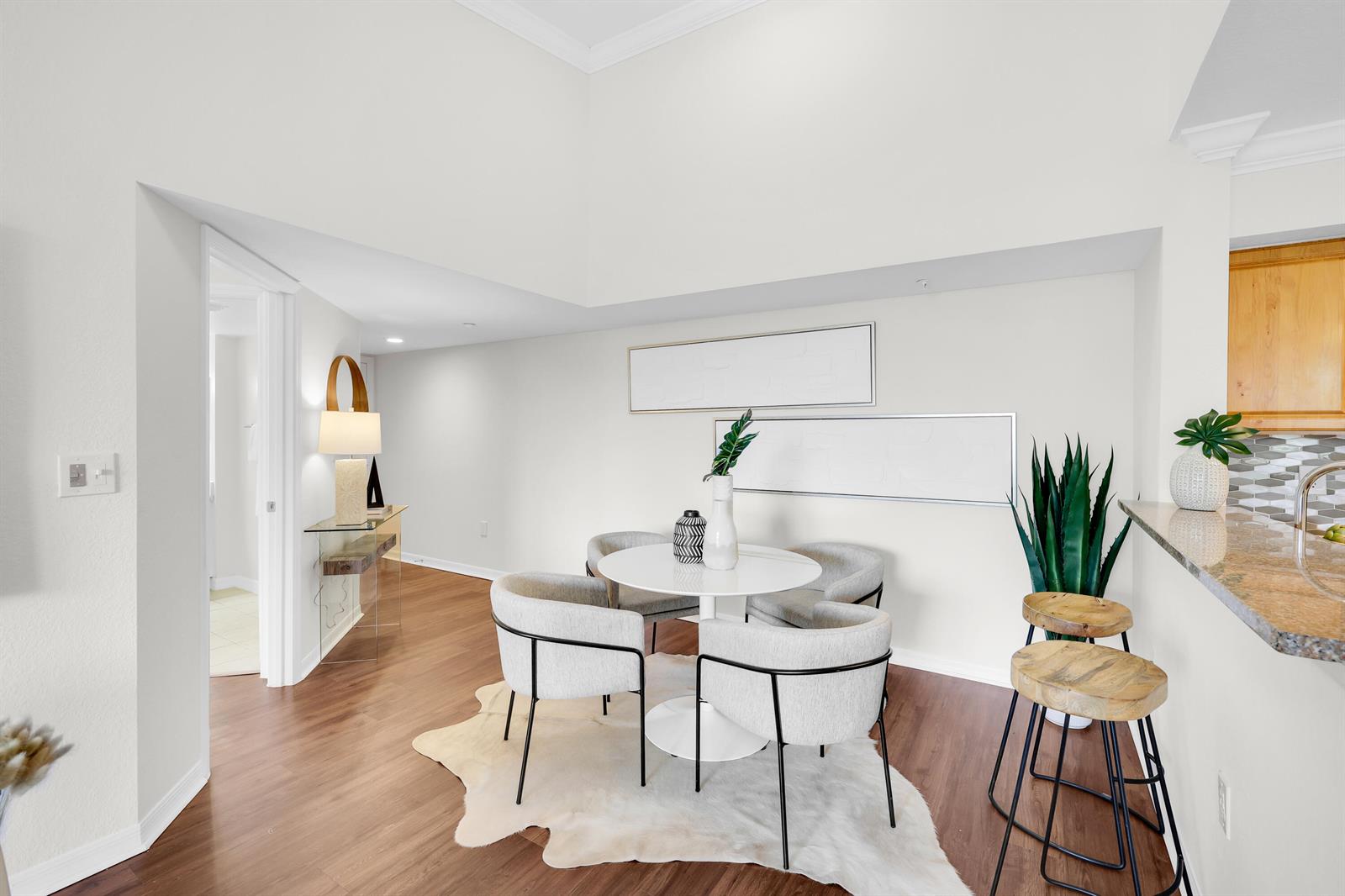 A dining area features a round table, four chairs, and a cowhide rug on wood flooring — 15035 Michelangelo Boulevard # 303, Delray Beach FL 33446, DELRAY BEACH, FL