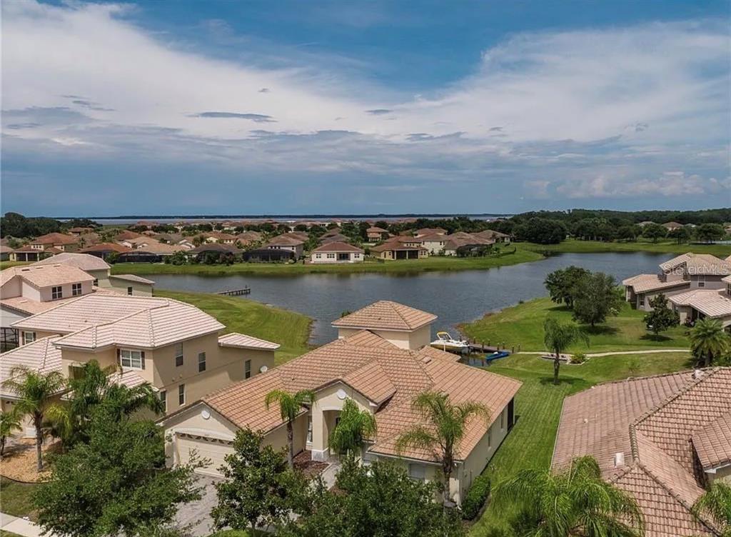 An aerial view of a residential neighborhood featuring houses with tile roofs near a lake — 3839 GOLDEN FEATHER WAY, KISSIMMEE, FL