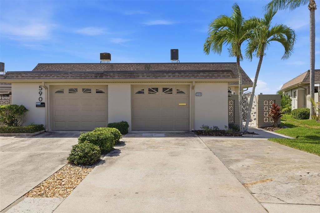 A single-story duplex building with two beige garage doors and palm trees in the front — 594 BOCA CIEGA POINT BOULEVARD N, ST PETERSBURG, FL