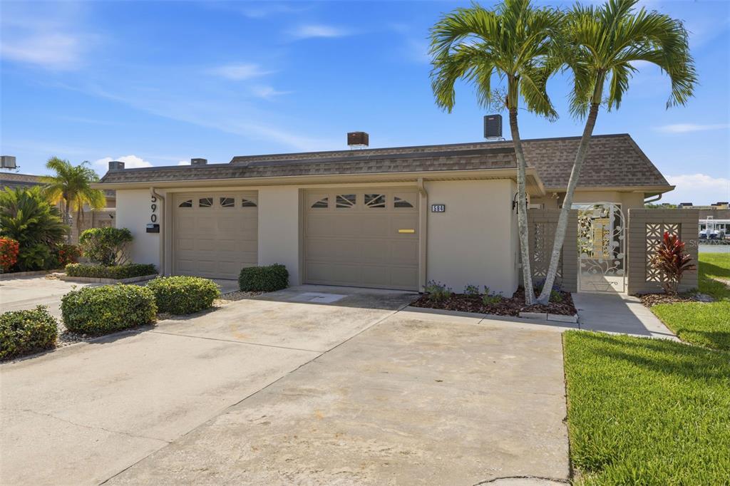 A single-story house exterior features two garage doors, a concrete driveway, and two palm trees — 594 BOCA CIEGA POINT BOULEVARD N, ST PETERSBURG, FL