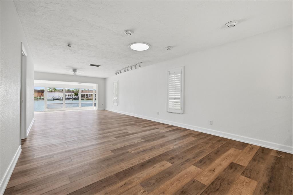 An empty room with wood-look flooring, a skylight, and large windows overlooking a canal — 594 BOCA CIEGA POINT BOULEVARD N, ST PETERSBURG, FL