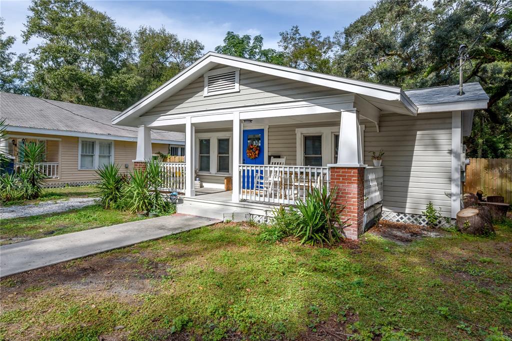 A light-colored bungalow with a front porch, brick-based columns, and a bright blue door — 806 E HAMILTON AVENUE, TAMPA, FL