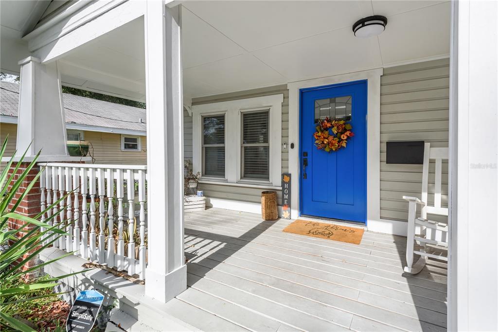A front porch with a blue door, white railings, and a wooden rocking chair — 806 E HAMILTON AVENUE, TAMPA, FL