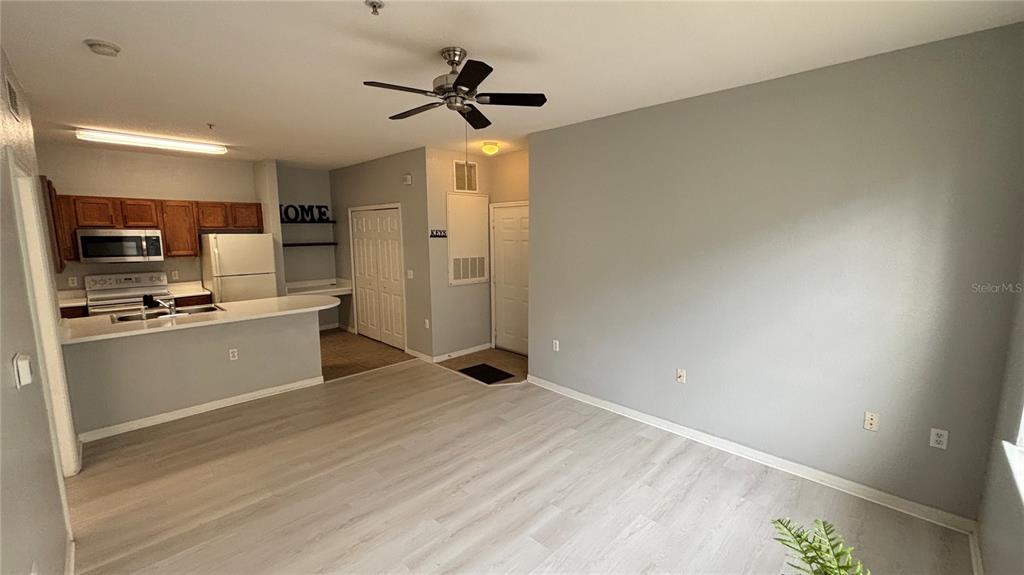 An open-concept kitchen with wood cabinets and a breakfast bar overlooks a living area — 8103 LILLIES WAY UNIT 108, ORLANDO, FL