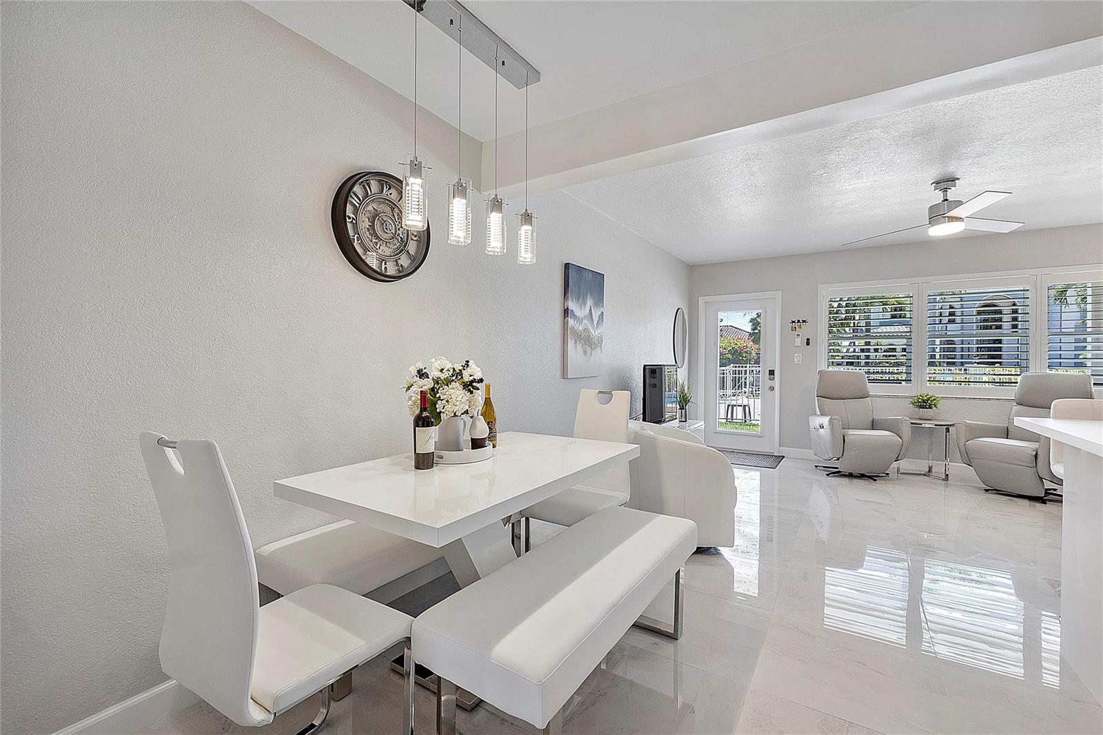 A bright dining area features a white table, benches, chairs, and glossy tiled flooring — 500 Layne Boulevard # 6, Hallandale Beach FL 33009, HALLANDALE BEACH, FL