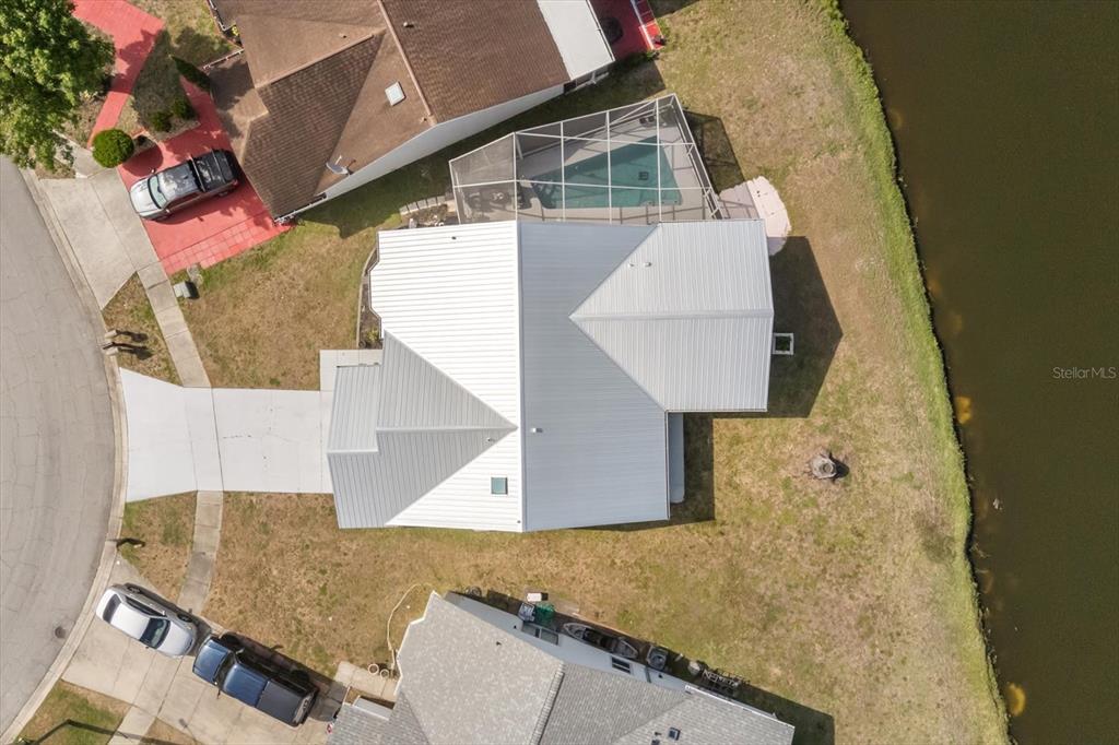 An aerial view shows a house with a metal roof, pool cage, and waterfront backyard — 988 DEER SPRINGS ROAD, PORT ORANGE, FL