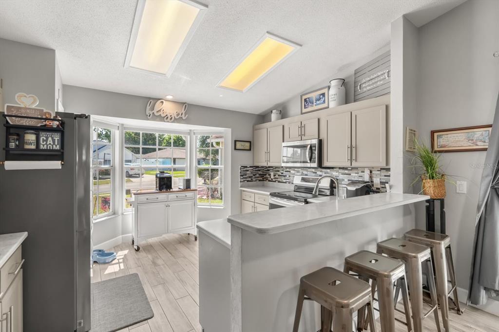 A kitchen features light gray cabinets, a breakfast bar with stools, and a bay window — 988 DEER SPRINGS ROAD, PORT ORANGE, FL