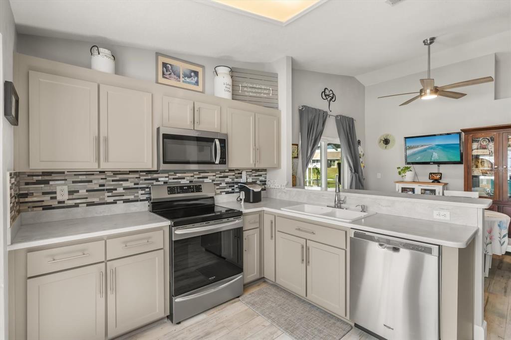 A kitchen features light gray cabinets, stainless steel appliances, and a tiled backsplash — 988 DEER SPRINGS ROAD, PORT ORANGE, FL
