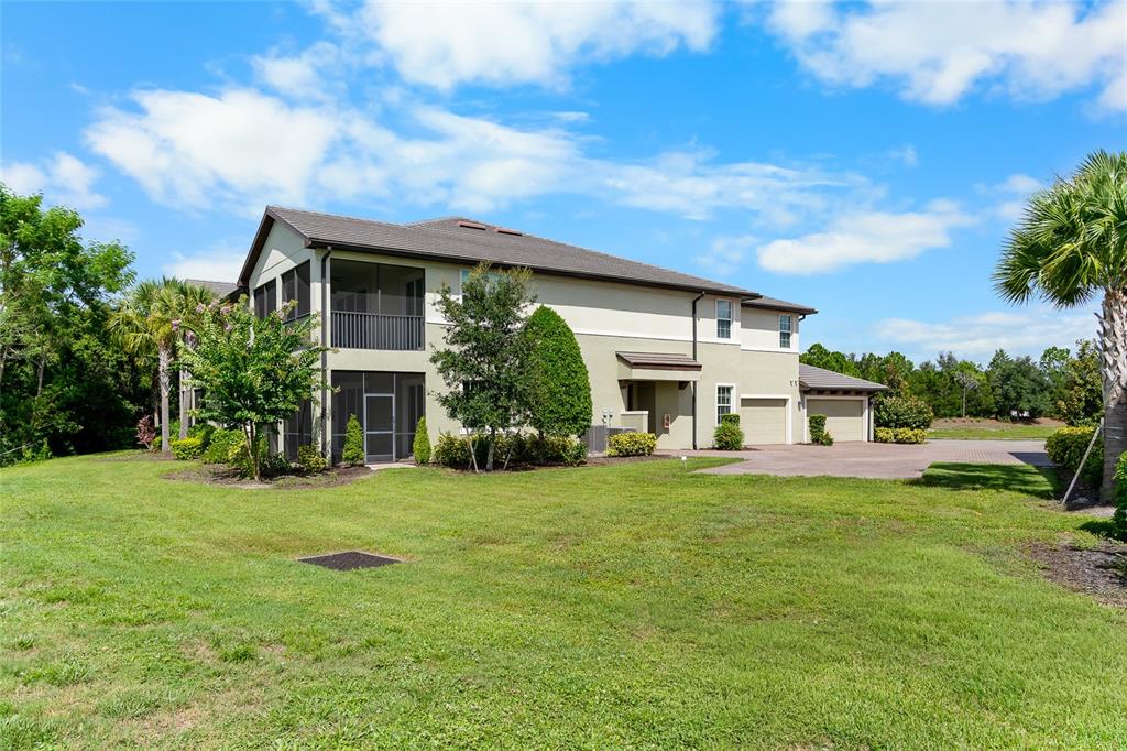 A two-story multi-family building with a screened-in porch and attached garages on a lawn — 7342 DIVOT LOOP UNIT 1, LAKEWOOD RANCH, FL