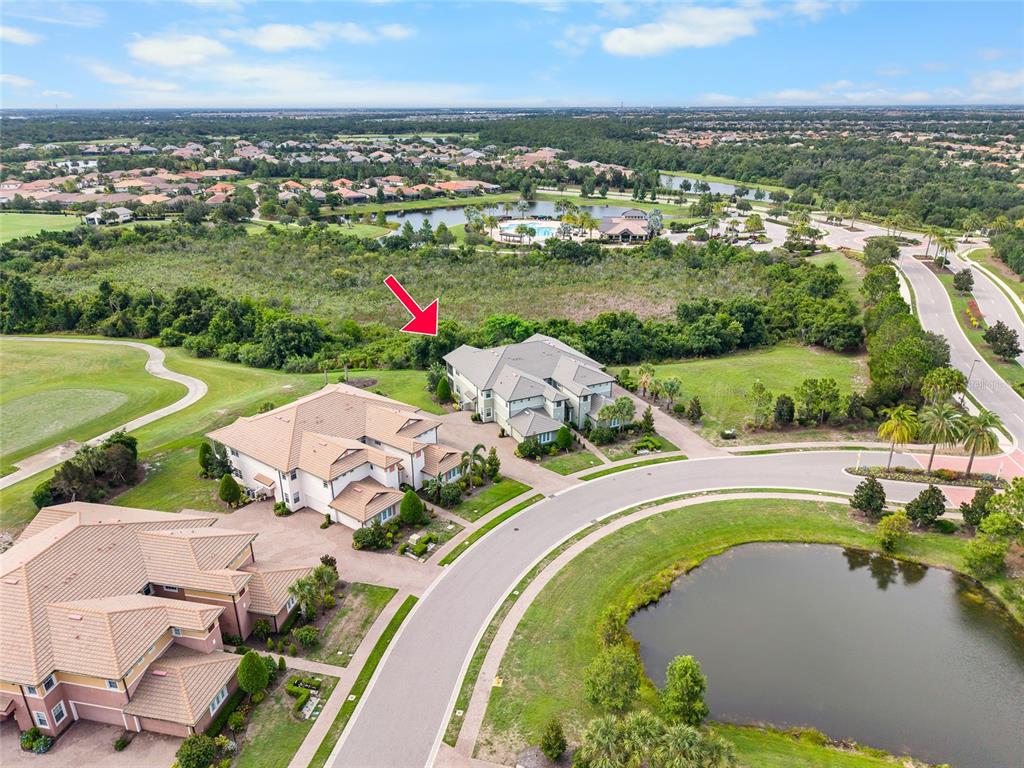 An aerial view shows several large houses situated near a pond and wooded area — 7342 DIVOT LOOP UNIT 1, LAKEWOOD RANCH, FL