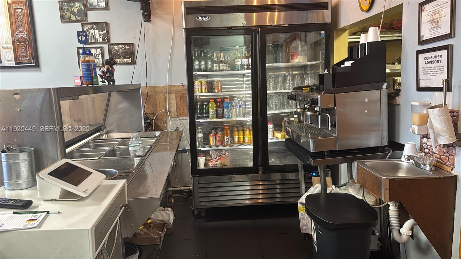 A commercial kitchen area features a stainless steel prep counter, refrigerator, and espresso machine — 22069 S Dixie Hwy, Miami FL 33170, MIAMI, FL