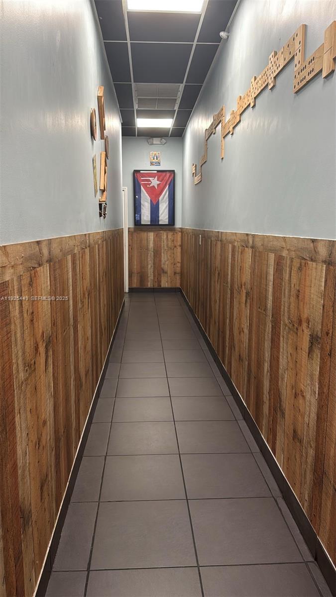 A narrow hallway features wood-paneled wainscoting, gray tiled floors, and a framed Cuban flag — 22069 S Dixie Hwy, Miami FL 33170, MIAMI, FL