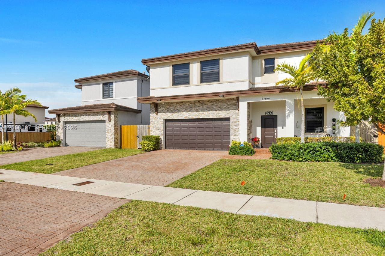 A two-story suburban house features a stone facade, a brown garage, and a paved driveway — 24970 SW 108th Ave, Homestead FL 33032, HOMESTEAD, FL