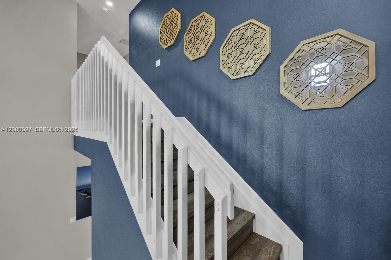 A staircase with white railings ascends along a blue wall decorated with four geometric ornaments — 24970 SW 108th Ave, Homestead FL 33032, HOMESTEAD, FL