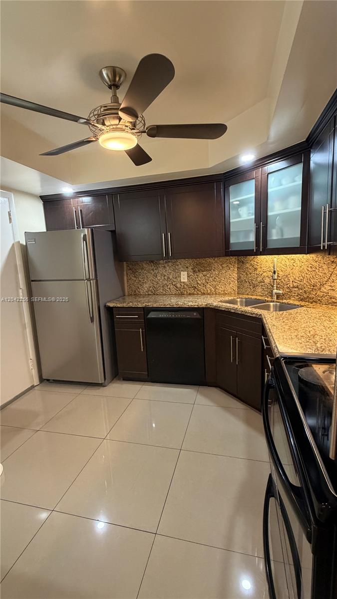 A kitchen features dark wood cabinets, granite countertops, stainless steel appliances, and light tile flooring — 3280 Spanish Moss Ter # 214, Lauderhill FL 33319, LAUDERHILL, FL