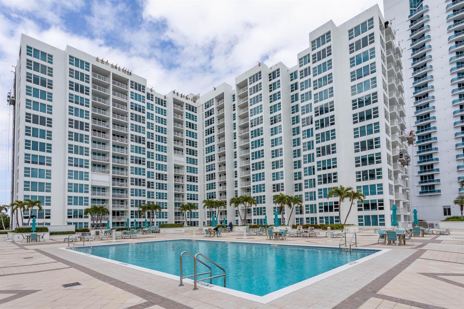 A swimming pool sits on a paved deck in front of a large white apartment building — 1620 S Ocean Boulevard # 7K, Pompano Beach FL 33062, POMPANO BEACH, FL