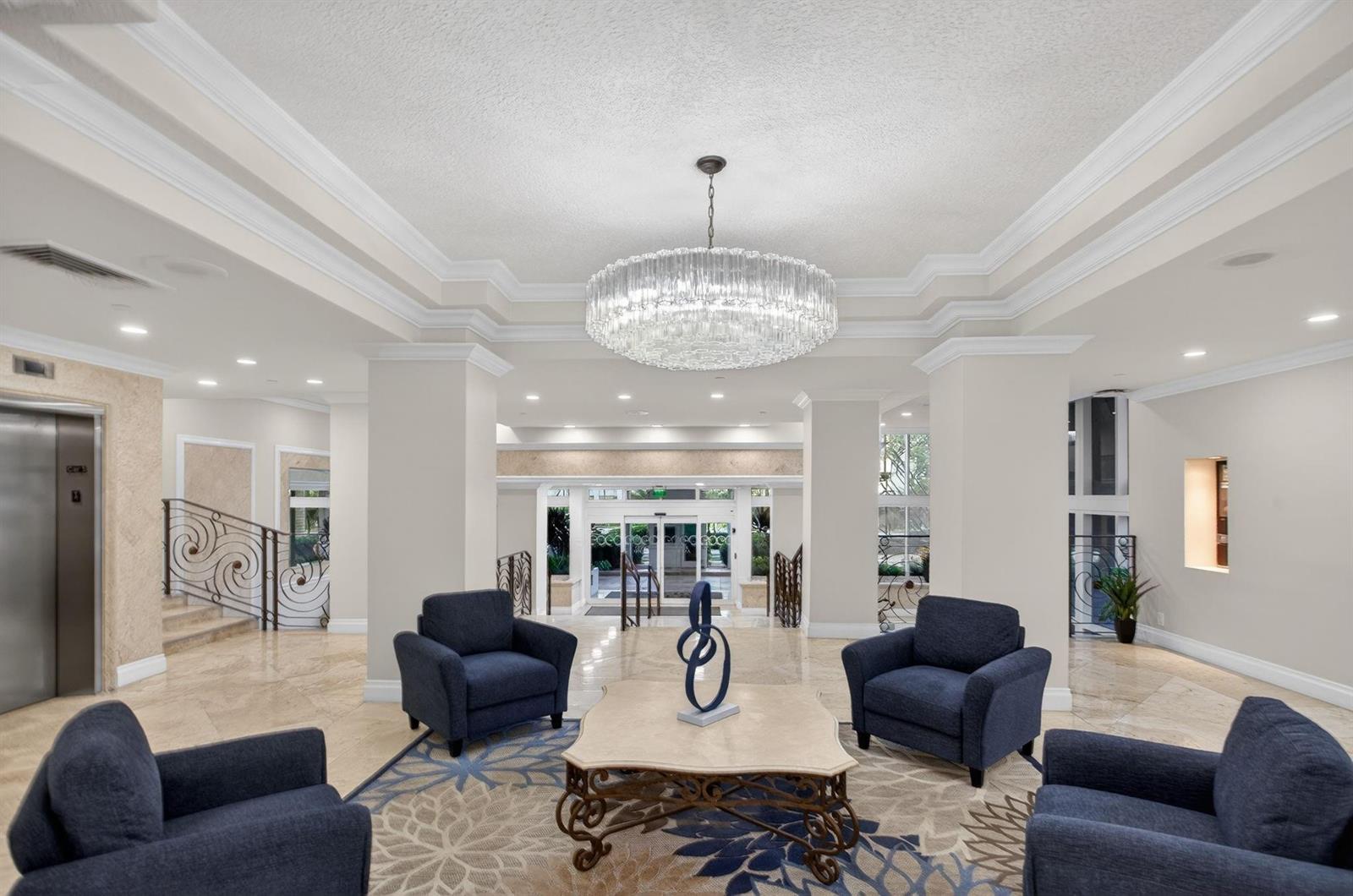 A bright lobby features four navy armchairs, a central coffee table, and a large crystal chandelier — 1620 S Ocean Boulevard # 7K, Pompano Beach FL 33062, POMPANO BEACH, FL