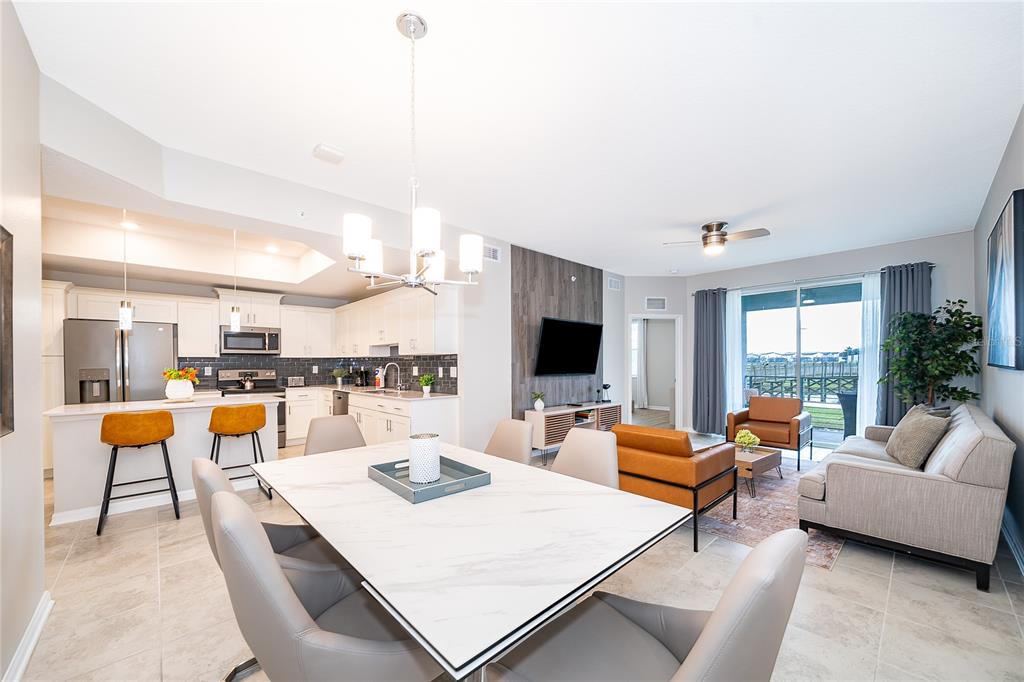 An open-concept kitchen, dining area, and living room featuring a marble-topped table and tile flooring — 3131 PARADOX CIRCLE UNIT 108, KISSIMMEE, FL