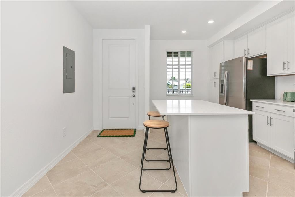 A kitchen with white cabinets, a quartz island, two bar stools, and a tile floor — 12320 WELLEN GOLF STREET UNIT 204, VENICE, FL