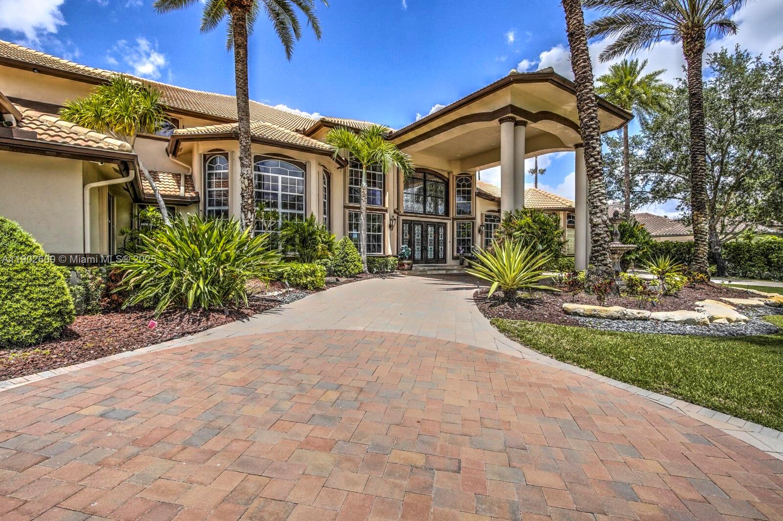 A paved driveway leads to the grand entrance of a large, two-story stucco home — 3828 Pine Lake Dr, Weston FL 33332, WESTON, FL