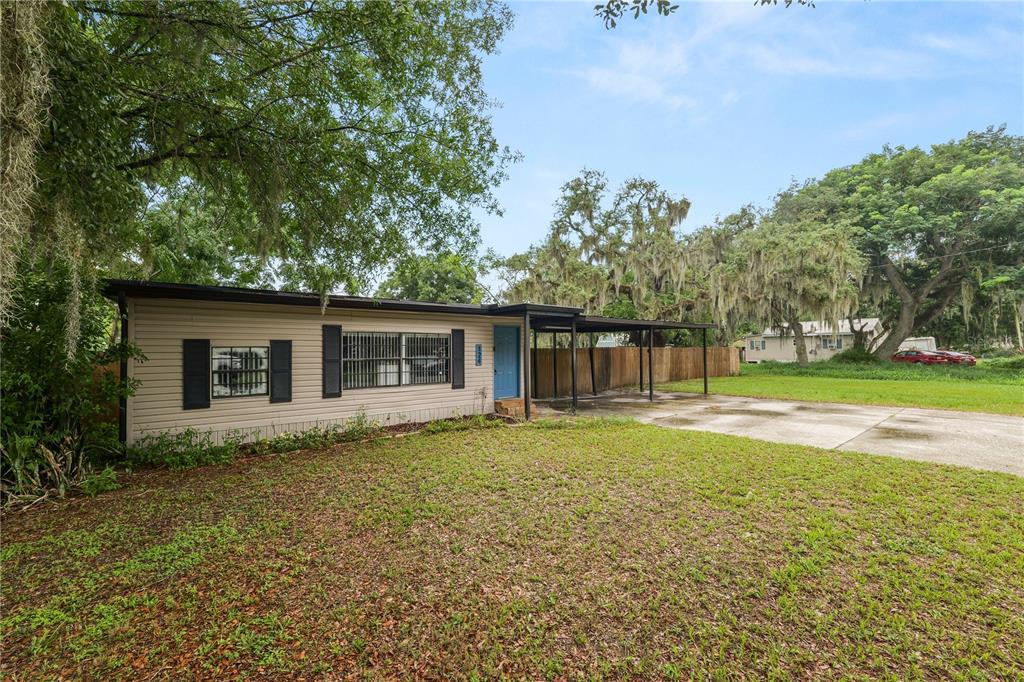 A single-story house with light siding, a blue front door, and an attached carport — 124 GRIFFIN AVENUE, LAKELAND, FL