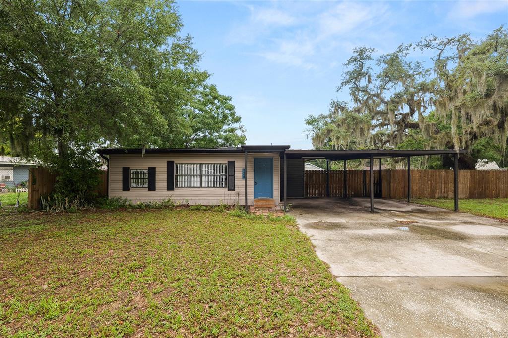 A single-story house with beige siding, a blue front door, and an attached carport — 124 GRIFFIN AVENUE, LAKELAND, FL