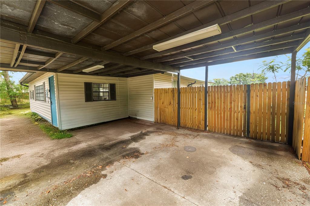 A concrete carport with a wooden fence and a light-colored siding exterior wall — 124 GRIFFIN AVENUE, LAKELAND, FL