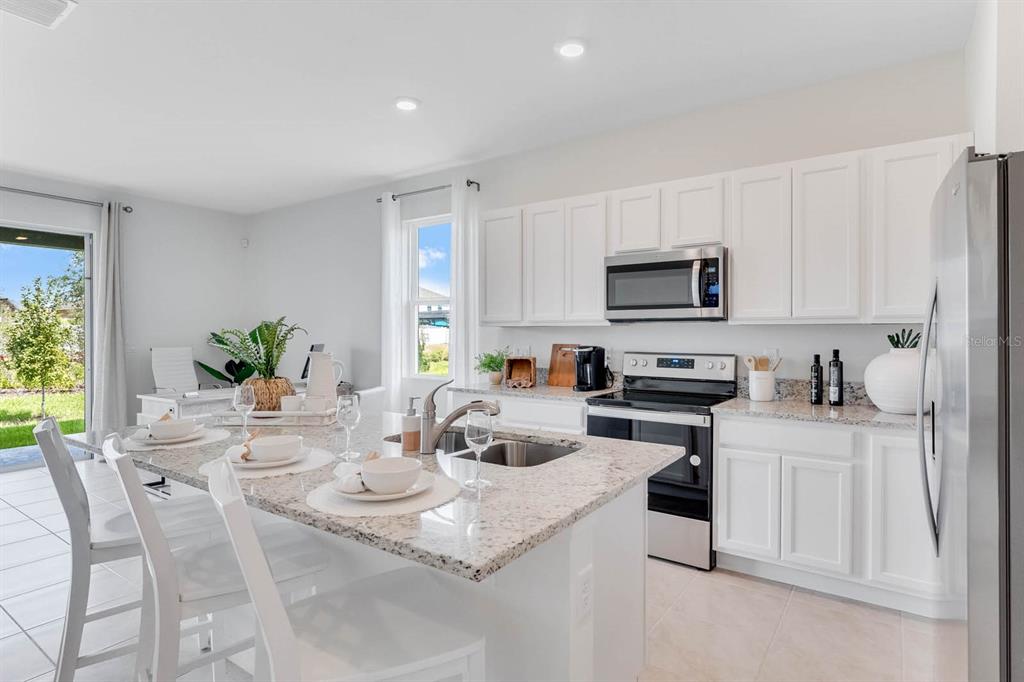 A kitchen features white cabinets, granite countertops, a stainless steel oven, and a center island — 2634 OLYMPIC COURT, DAVENPORT, FL