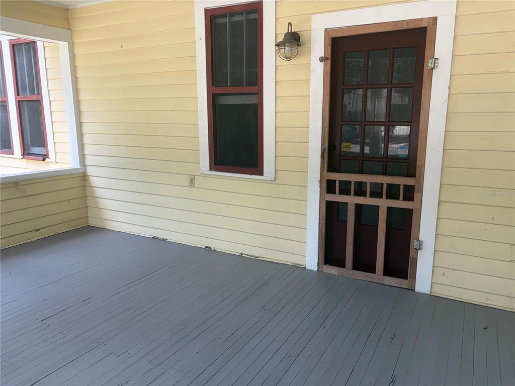 A yellow-sided porch features a grey floor, a screen door, and two windows — 1555 7TH STREET, SARASOTA, FL