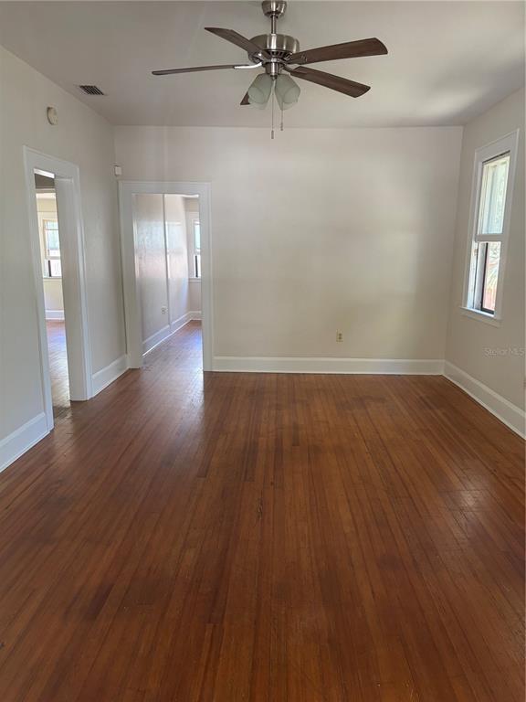 An empty room features hardwood floors, a ceiling fan, and two doorways leading to other rooms — 1555 7TH STREET, SARASOTA, FL