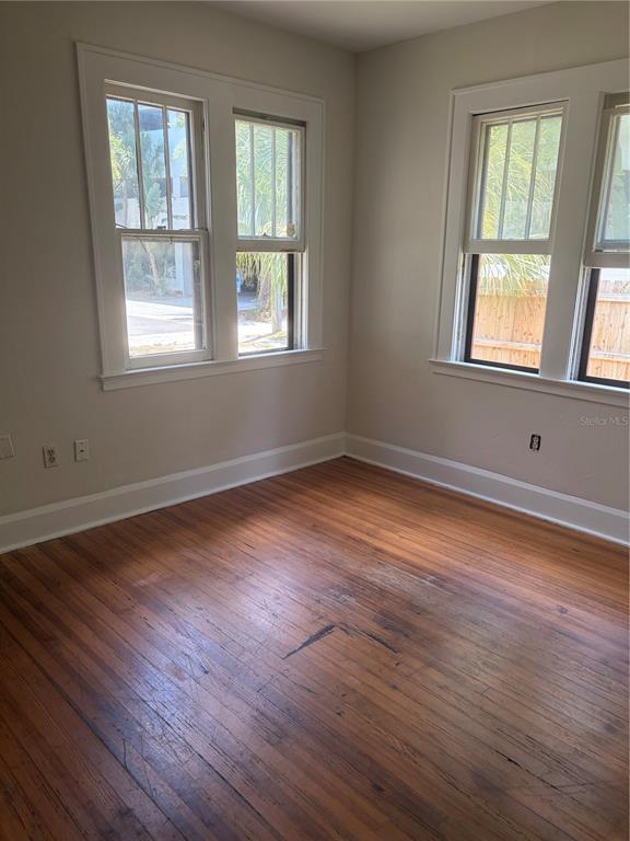 An empty room with hardwood floors, white trim, and two sets of windows — 1555 7TH STREET, SARASOTA, FL