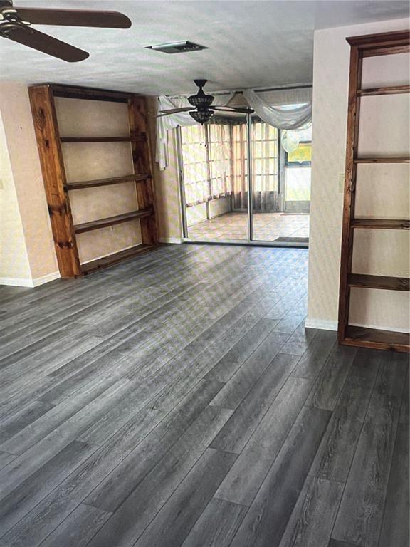 A room with gray wood-look flooring, two built-in wooden bookshelves, and a sliding glass door — 7202 GULF HIGHLANDS DRIVE, PORT RICHEY, FL