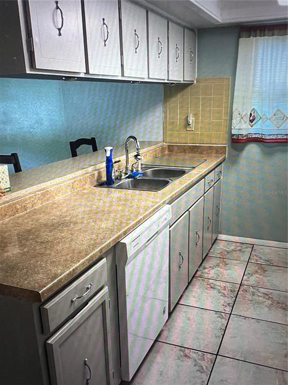 A kitchen features light gray cabinets, a tan laminate countertop, a double sink, and tiled flooring — 7202 GULF HIGHLANDS DRIVE, PORT RICHEY, FL