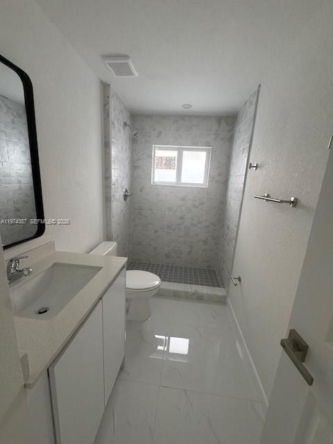 A modern bathroom features a white vanity, a toilet, and a tiled walk-in shower — 3131 NW 60 St. # 0, Miami FL 33142, MIAMI, FL