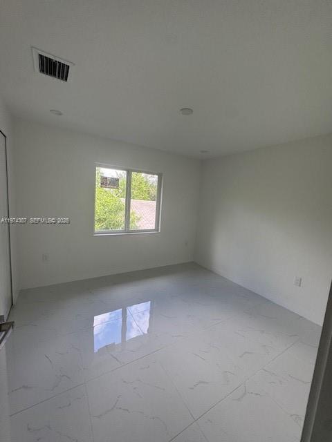 An empty room features white walls, recessed lighting, and light-colored marble-style tile flooring — 3131 NW 60 St. # 0, Miami FL 33142, MIAMI, FL
