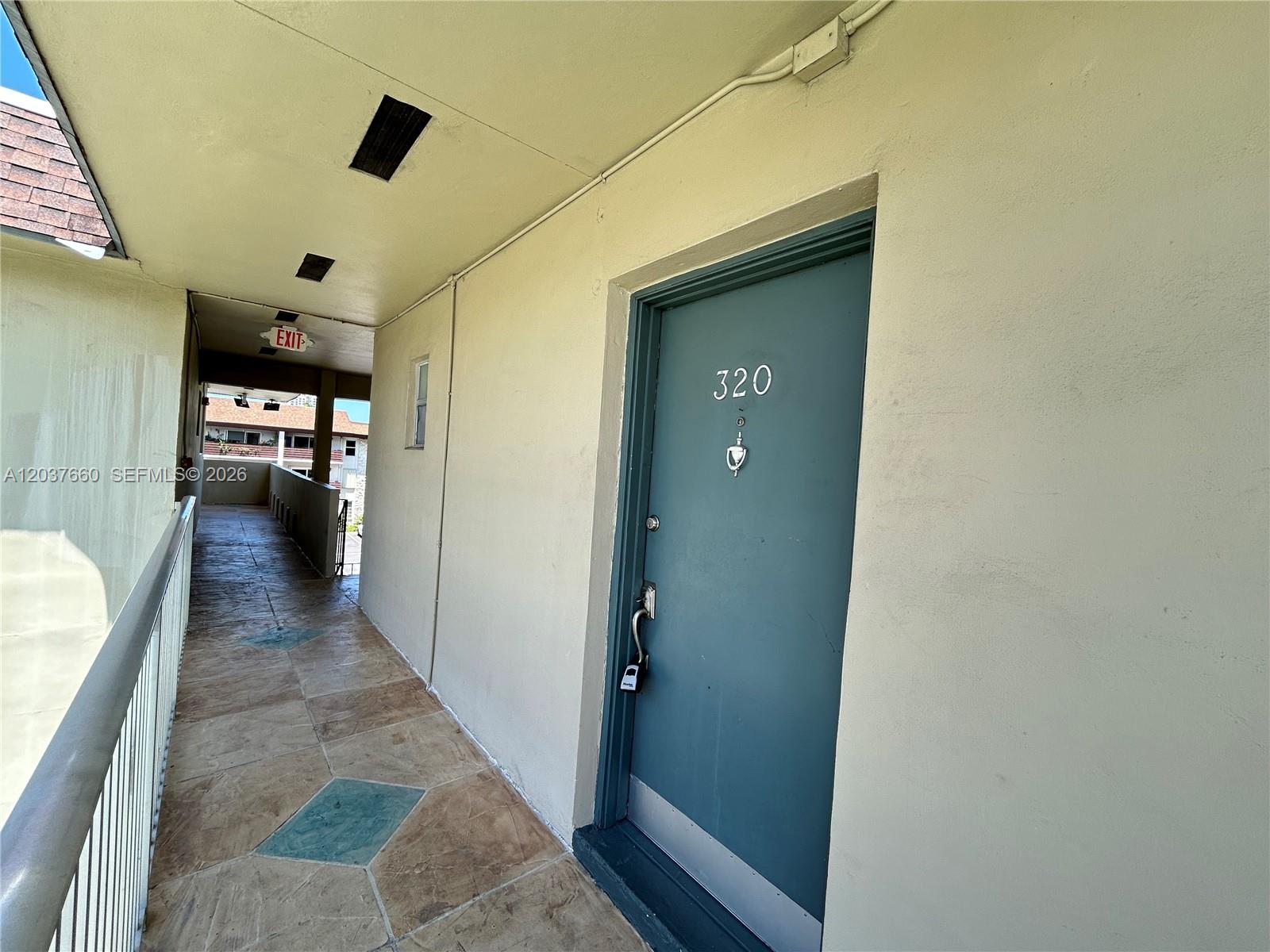 A blue apartment door numbered 320 is located along an outdoor walkway with tiled flooring — 7505 SW 82nd St # 320, Miami FL 33143, MIAMI, FL