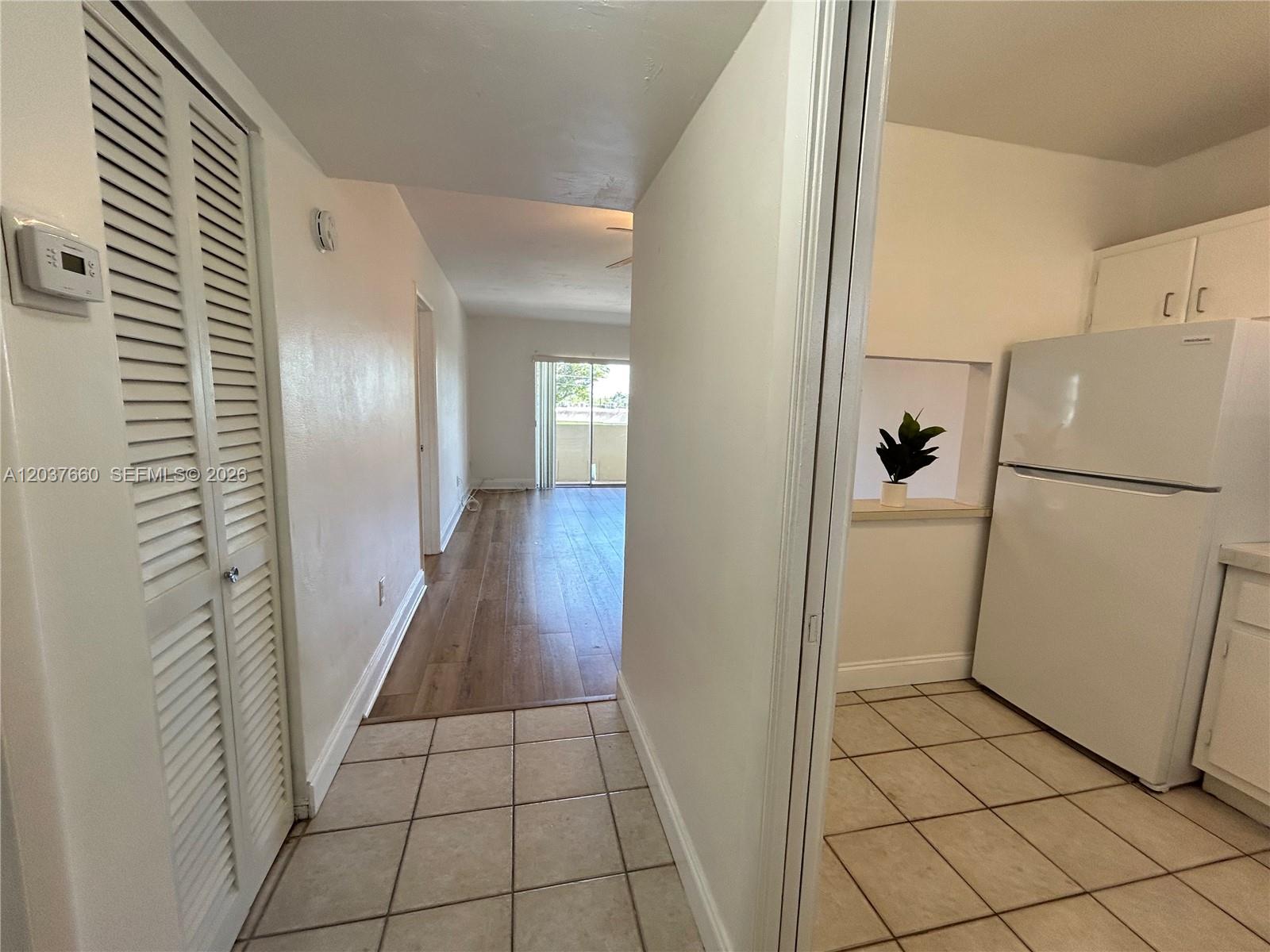 A hallway with tiled floors leads to a living area with wood-look flooring and balcony — 7505 SW 82nd St # 320, Miami FL 33143, MIAMI, FL
