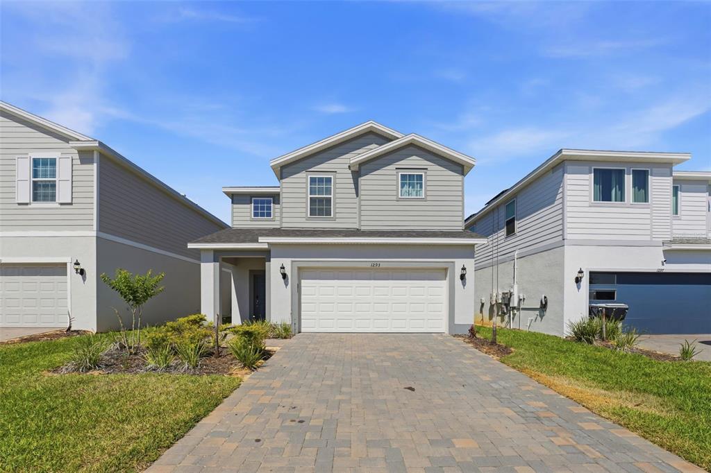 A two-story house with light gray siding, a two-car garage, and a paved driveway — 1293 EMERALD ROW STREET, CLERMONT, FL