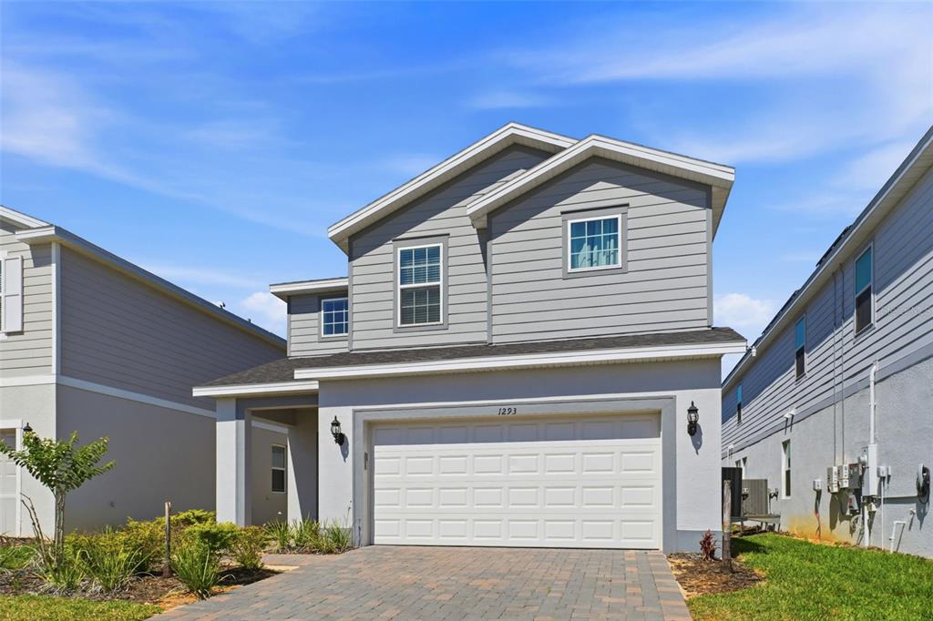 A two-story house with gray horizontal siding, a two-car garage, and a paved driveway — 1293 EMERALD ROW STREET, CLERMONT, FL