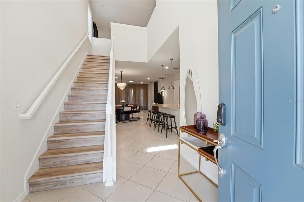 An entryway features a staircase, tile flooring, and an open view into the dining area — 1293 EMERALD ROW STREET, CLERMONT, FL