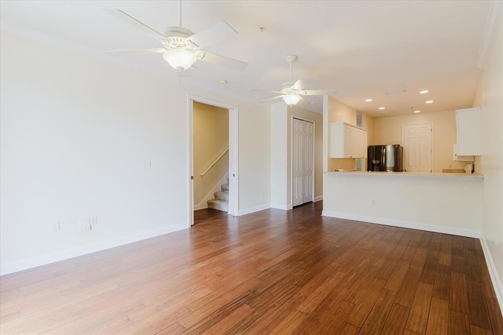 An open-concept living area features hardwood floors, two ceiling fans, and an adjacent kitchen — 6825 S KISSIMMEE STREET, TAMPA, FL